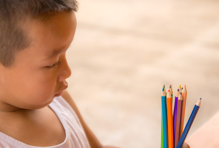 Closeup portrait of a little boy look at colorful pencilsの写真素材