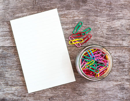 Open blank notebook with paper clips over a wooden backgroundの写真素材