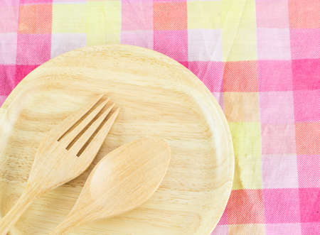 Wooden spoon and  fork in wooden plate on a tableclothの写真素材