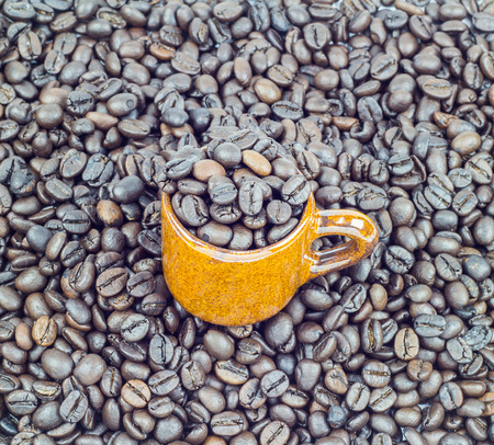 Coffee beans in ceramic cup on coffee beans backgroundの写真素材