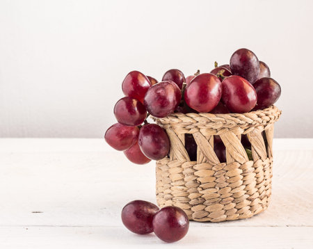 Red grapes in basketl on a wooden table backgroundの写真素材