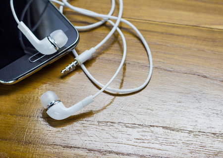 Close up smartphone and earphones on wooden tableの写真素材