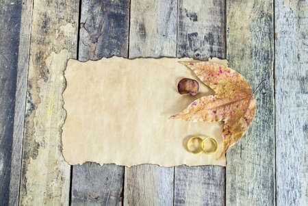 Close up gold ring, dry leaves and old paper on wooden backgroundの写真素材