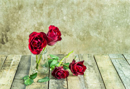 Fresh red rose in glass bottle on wooden backgroundの写真素材