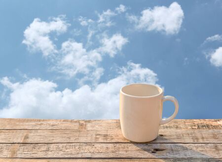 White Coffee cup on wooden table at morning sunlight and blue sky backgroundの写真素材