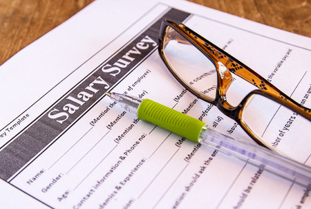 Glasses and pen on salary survey from on the tableの写真素材