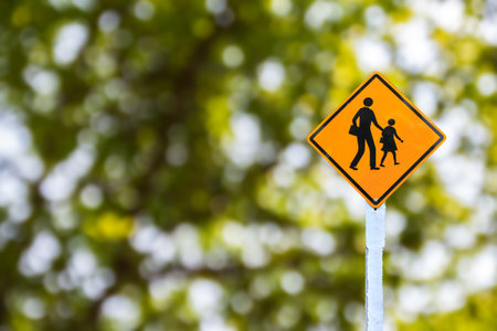 Yellow traffic sign on green blurred bokeh background