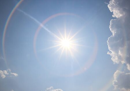 Sun in blue sky with white cloudの写真素材