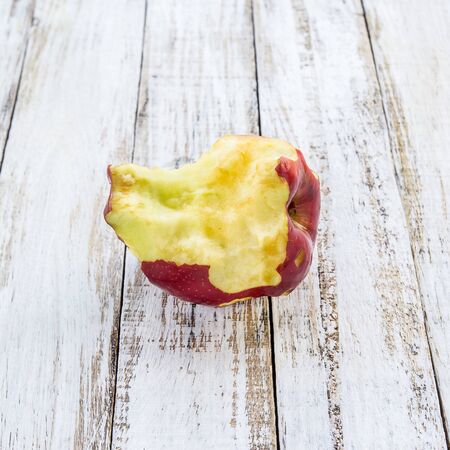 A bitten apple on white wooden table backgroundの写真素材