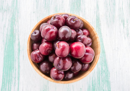 Fresh red Cherries in wooden bowl on wooden table background