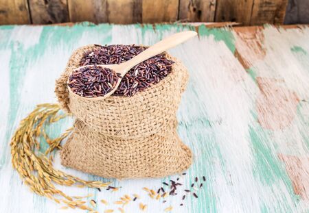 Close up raw purple rice berry in burlap sack on wooden backgroundの写真素材
