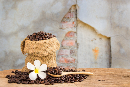 Coffee beans in burlap sack on wooden table with blurred grunge cracked backgroundの写真素材