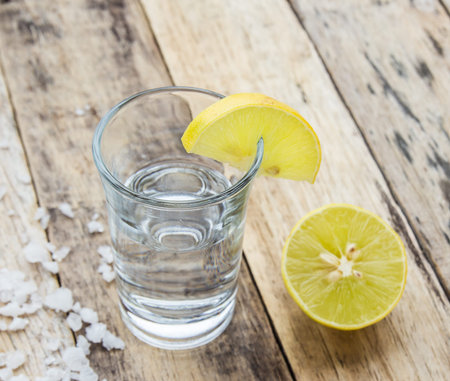 Vodka with lemon on wooden table background