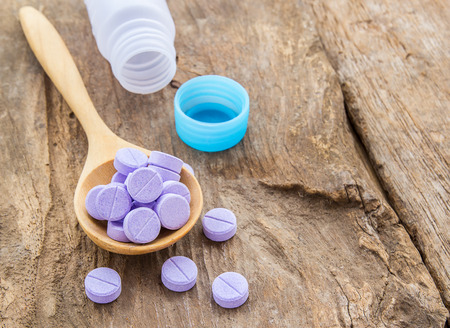Medical pills in wooden spoon on wooden table backgroundの写真素材