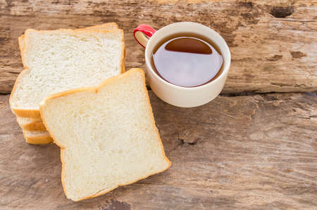 Slice of bread and tea in wooden plate on wooden backgroundの写真素材