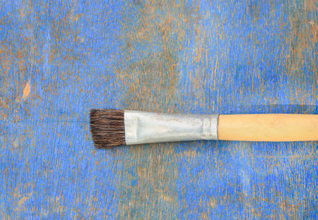 Paint brush on blue wooden table background.