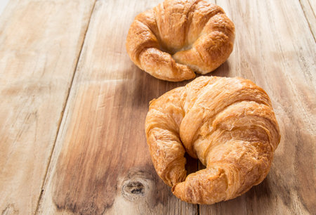 Fresh croissants on old wooden table background
