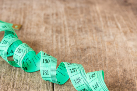 Close up green measuring tape on wooden table backgroundの写真素材