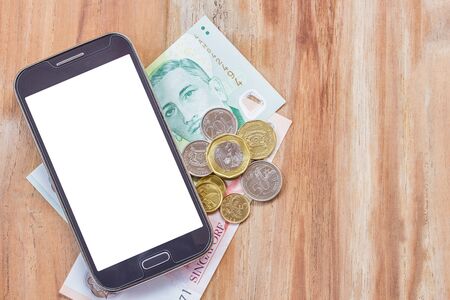 Smart phone and singapore dollar on wooden table backgroundの写真素材