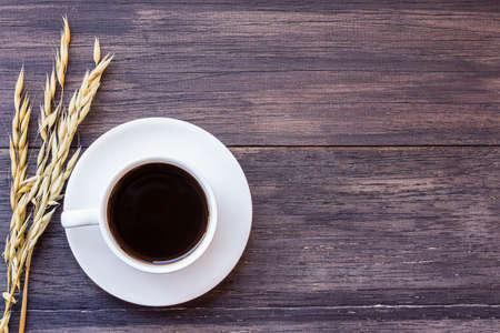 Cup of coffee and ears of oat on dark wooden table background. top view with copy spaceの写真素材