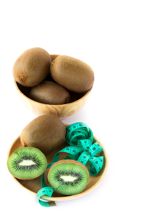 fresh kiwi and measuring tape in wooden pate on a white background - close upの写真素材