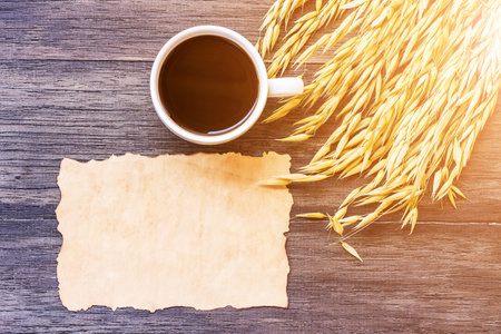 Ears of wheat and old paper with cup of coffee on dark wooden table background. top view with copy...