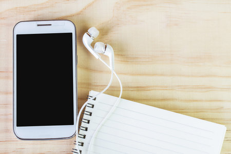 Smart phone and open notebook on wooden table. top viewの写真素材