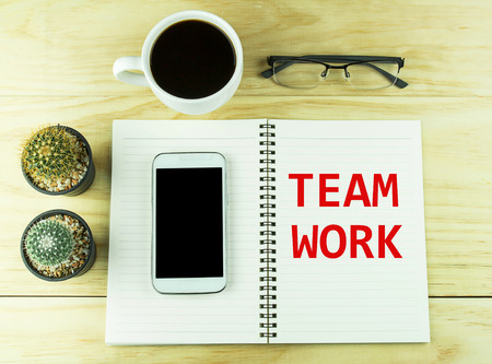 Smart phone, coffee,glasses and book blank with cactus on wood table background. Text for TEAM WORK on a book.top viewの写真素材