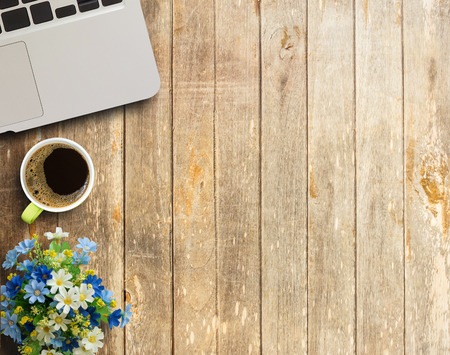 Office desk table with laptop computer, cup of coffee and flower. Top view with copy space (selective focus)の写真素材