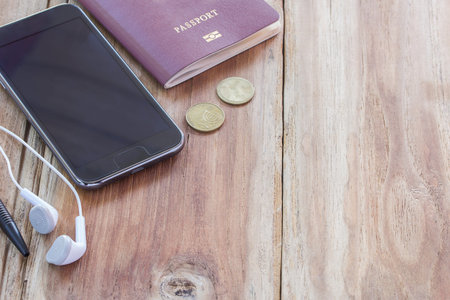 Smart phone and passport on wooden table with ear phone. copy spaceの写真素材