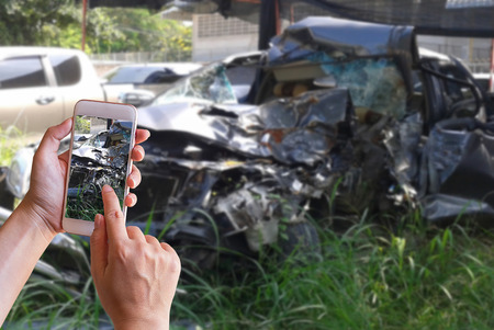 Hand of woman holding smart phone and take photo of the car accidentの写真素材