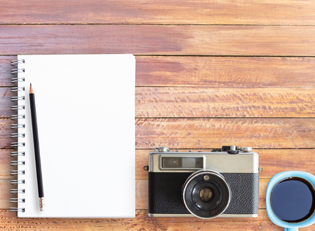 Top view of wooden table with office supplies. Office desk table with notebook,pencil and vintage camera. copy space for designの写真素材
