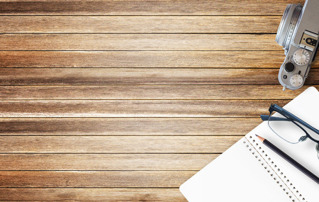 Office desk with blank notebook and black pencil on brown wood background. Top view with copy space for designの写真素材