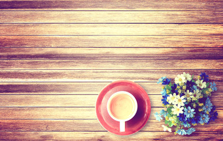 Cup of coffee and flower on wooden table background. Top view with copy space vintage styleの写真素材