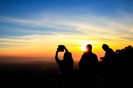 Silhouette of traveler standing over sunset and cloudy sky background.の写真素材