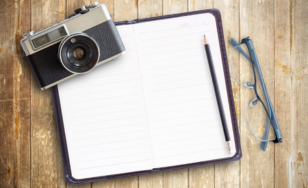 Old vintage camera and photo paper,notebook with glasses on wooden table. Top view with copy space for designの写真素材