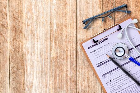 Workplace of a doctor. Stethoscope,claim form,glasses,pencil on wooden desk background. Top view with copy space. Healty concept.の写真素材