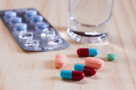 Close up pills and tablets with glass water on wooden table. Health and medical conceptの写真素材