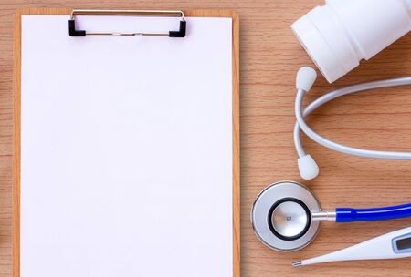 Workplace of a doctor. Stethoscope,thermometer and bottle of medicine on wooden desk background. Top view with copy space. Healty concept.の写真素材
