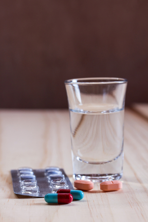 Close up pills and tablets with glass water on wooden table. Health and medical conceptの写真素材