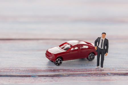 Miniature people : Businessman figures standing on the floor with blurred car background. money and financial concept. copy space for use as business background or wallpaper.の写真素材