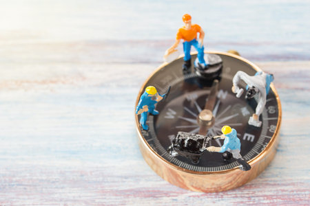 Miniature people- Figures construction worker, is working on a compass area with blurred background and sunlight.Business and construction conceptの写真素材