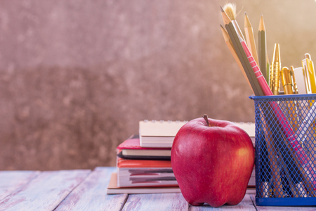 Back to school, Close up red apple,pencil and notebook or notepad with morning sunlight on wooden table with blurred background and copy space for design.の写真素材