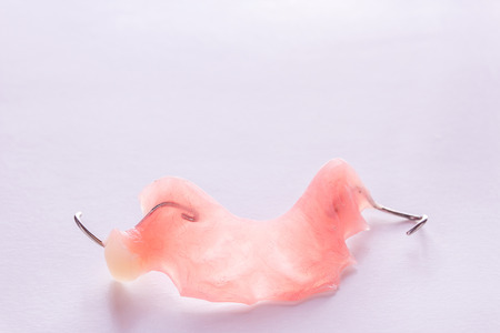 Close up acrylic denture with metal clasps for restoring dentition on white background. Health and medical concept.の写真素材