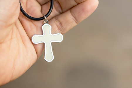 Christian cross in hand with blurred background with morning sunlight, christian concept Jesus is the light of the world, Copy space for designの写真素材
