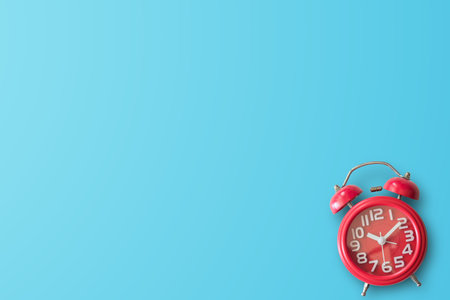 Red alarm clock in studio against blue background with empty place. space for text above, may be...