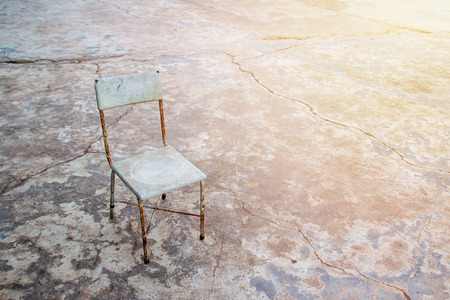Chair on the background of an old concrete wall with cracks stands on a cement floor background, space for text and design. tone with sunlight.の写真素材