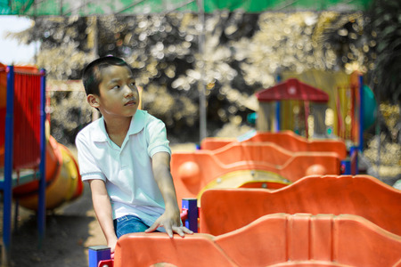 Cute asian child having fun at adventure park. Handsome boy smiling happily at children playground. Asian Caucasian mixed race toddler happily playing in a playground outside in the summer sunの写真素材