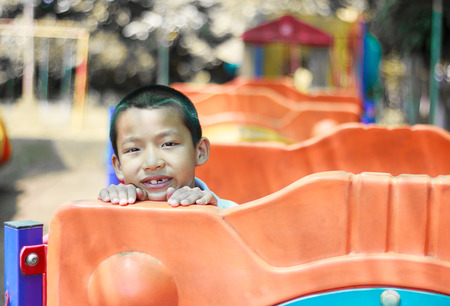 Cute asian child having fun at adventure park. Handsome boy smiling happily at children playground. Asian Caucasian mixed race toddler happily playing in a playground outside in the summer sunの写真素材