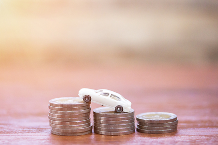Toy car and coin stacks on wood tableの写真素材